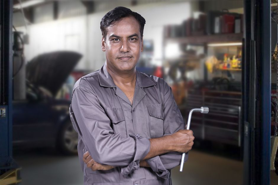 Smiling auto mechanic standing near a vehicle
